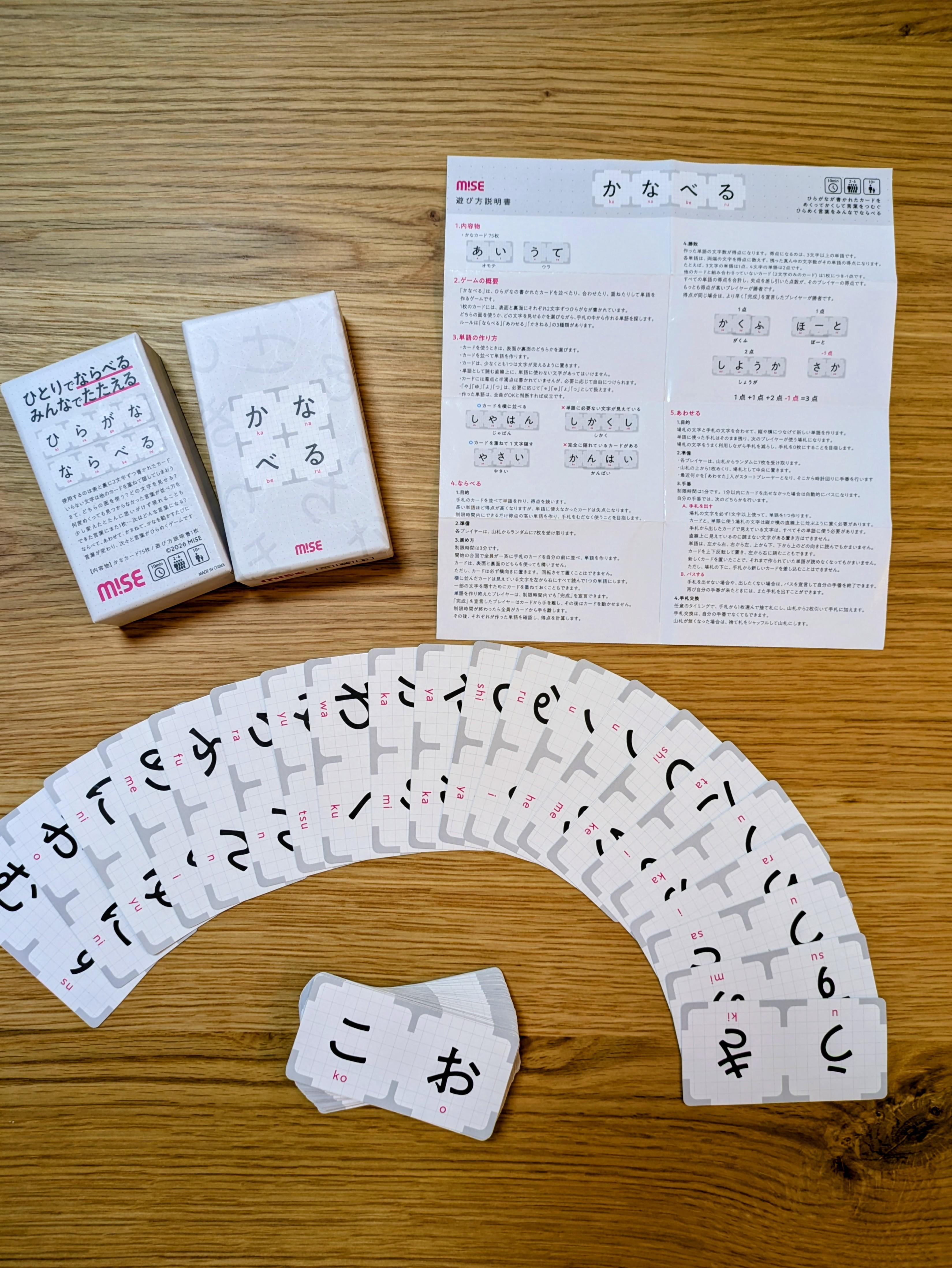 開いた『かなべる』の箱と75枚のかなカード、遊び方説明書